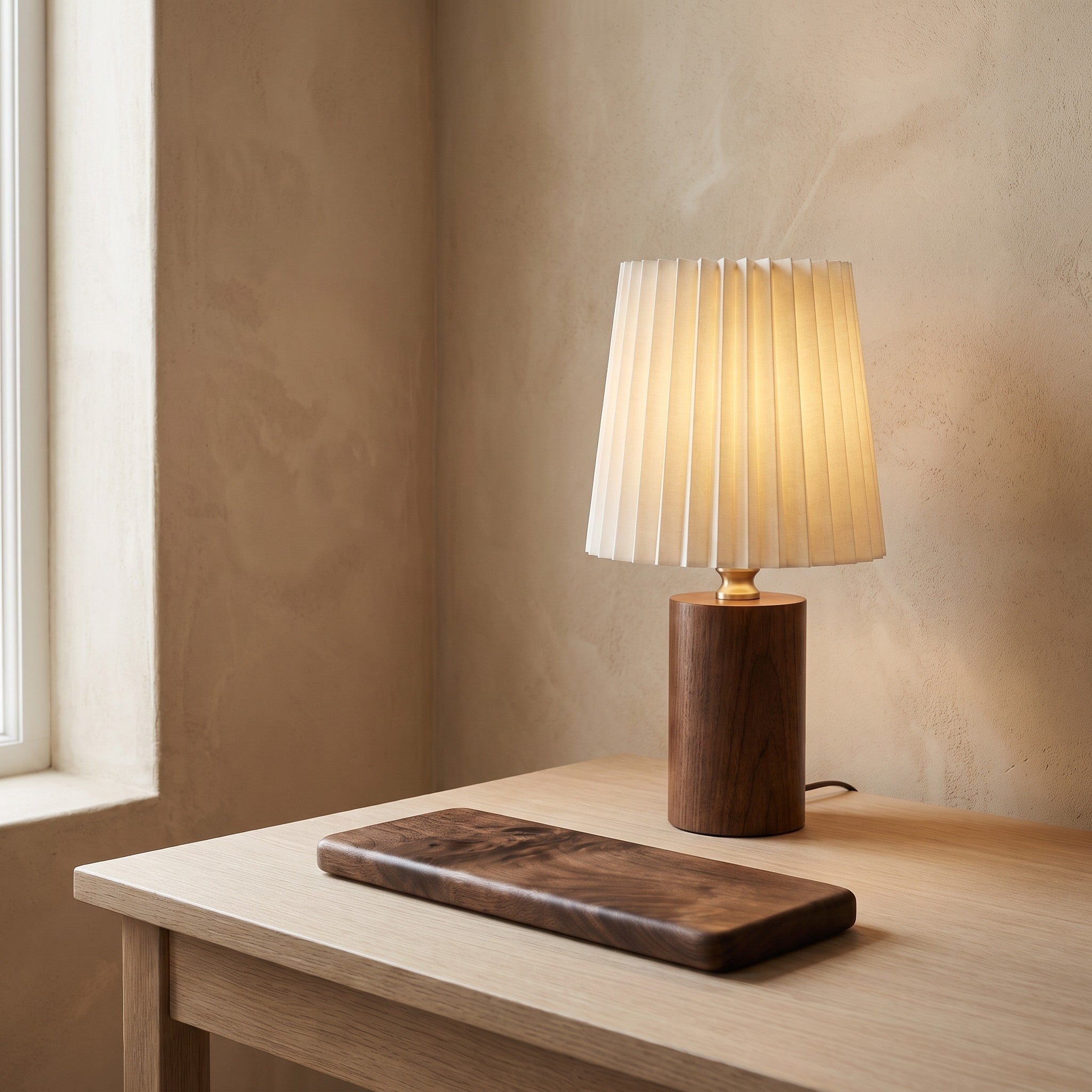 A walnut-finish wrist rest and desk lamp on a white oak desk against a warm plaster wall