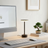 Modern desk setup with computer monitor, keyboard, mouse, and lamp in a bright room.