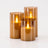 Set of three flameless LED pillar candles in three heights on a plain off-white background