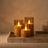 Three flameless LED candles lit on a travertine tray in low evening light