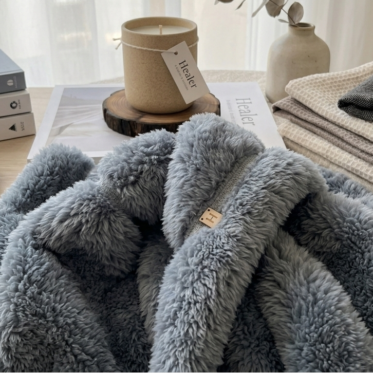 Cozy scene with a gray textured blanket, books, and decorative items on a table.