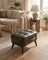 Tufted faux leather ottoman styled in a living room scene