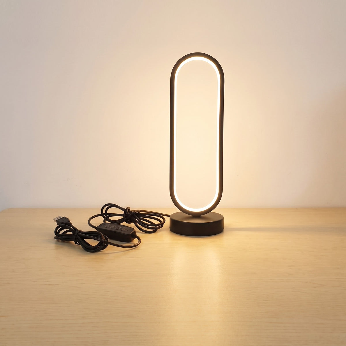 Black oval ring desk lamp lit on a desk