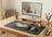 Wooden desk with computer setup, including monitor, keyboard, and mouse, in a home office setting.