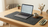 Laptop on a desk with a mouse pad, coffee cup, and stationery items.