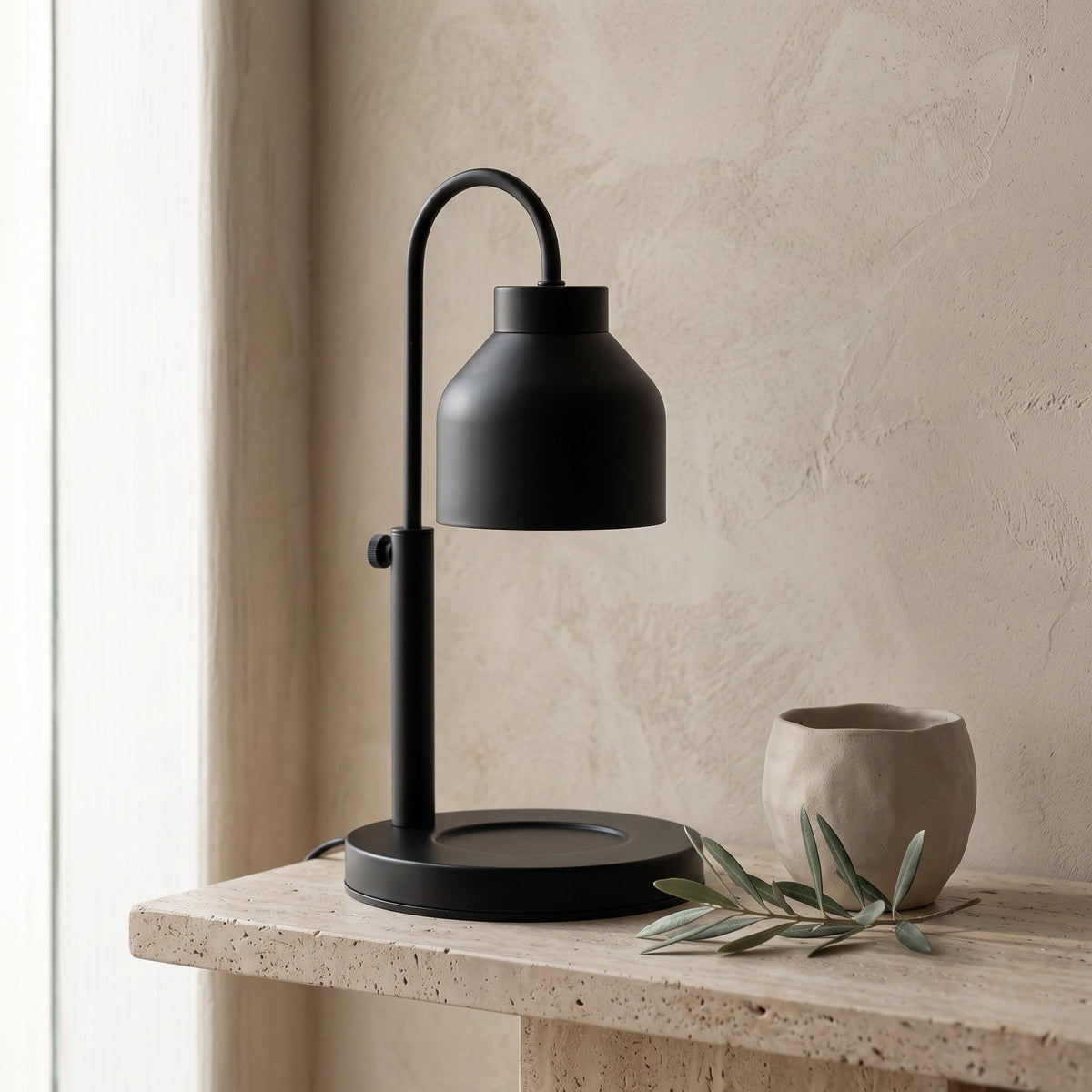 Dual-bulb candle warmer lamp in black, unlit on a travertine shelf in a warm room scene