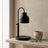 Dual-bulb candle warmer lamp in black, unlit on a travertine shelf in a warm room scene
