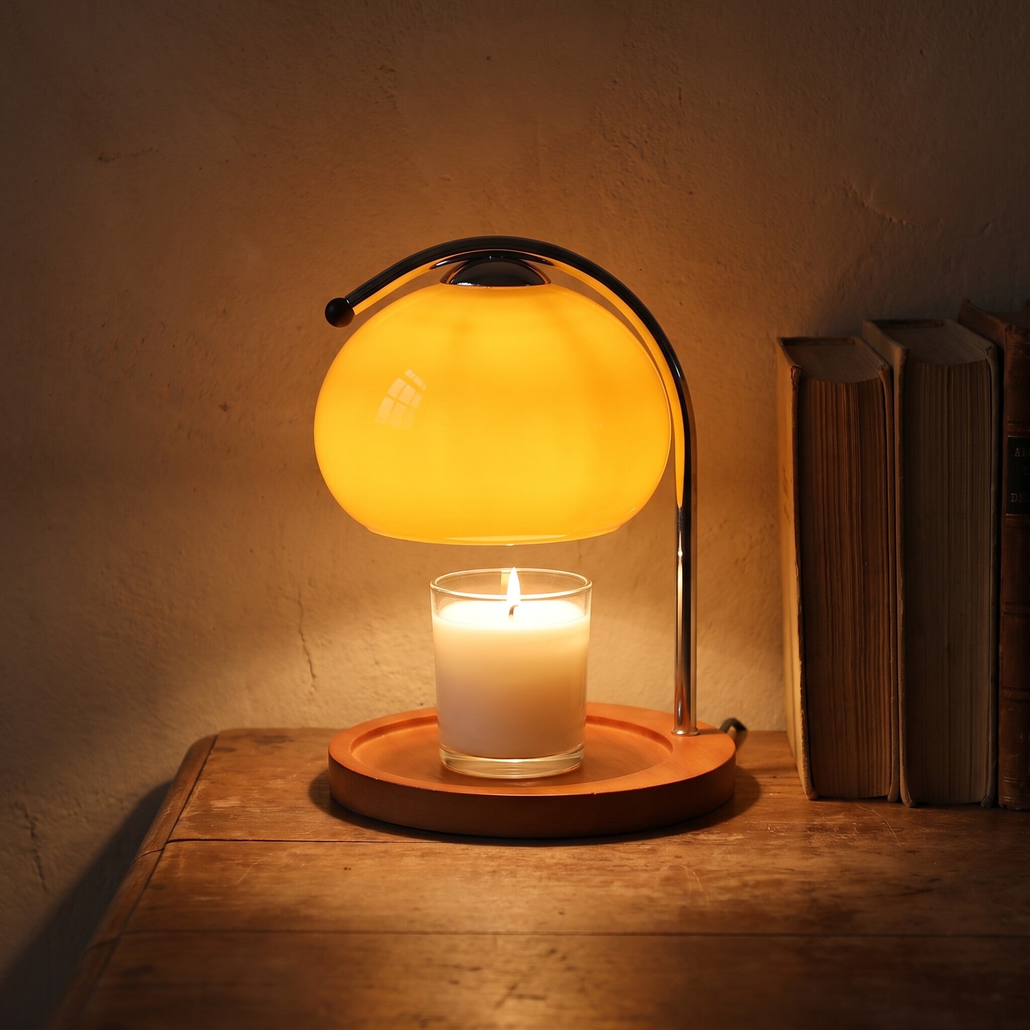 Glass candle warmer lamp lit over a jar candle on a desk at night, candle not included