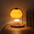 Glass candle warmer lamp lit over a jar candle on a desk at night, candle not included