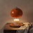 Glass candle warmer lamp lit over a jar candle on a walnut side table in evening light, candle not included