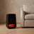 Flame effect ceramic heater running beside a linen armchair on a white oak floor