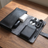 PU leather tech organizer case, black finish, open on a desk with charging cables secured in the loops
