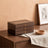 Warm Wood-Grain Tiered Jewelry Box closed on a walnut dresser beside a ceramic dish and a folded linen runner.