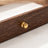 Close-up of a brass-tone knob on the wood-grain drawer front of the Warm Wood-Grain Tiered Jewelry Box.