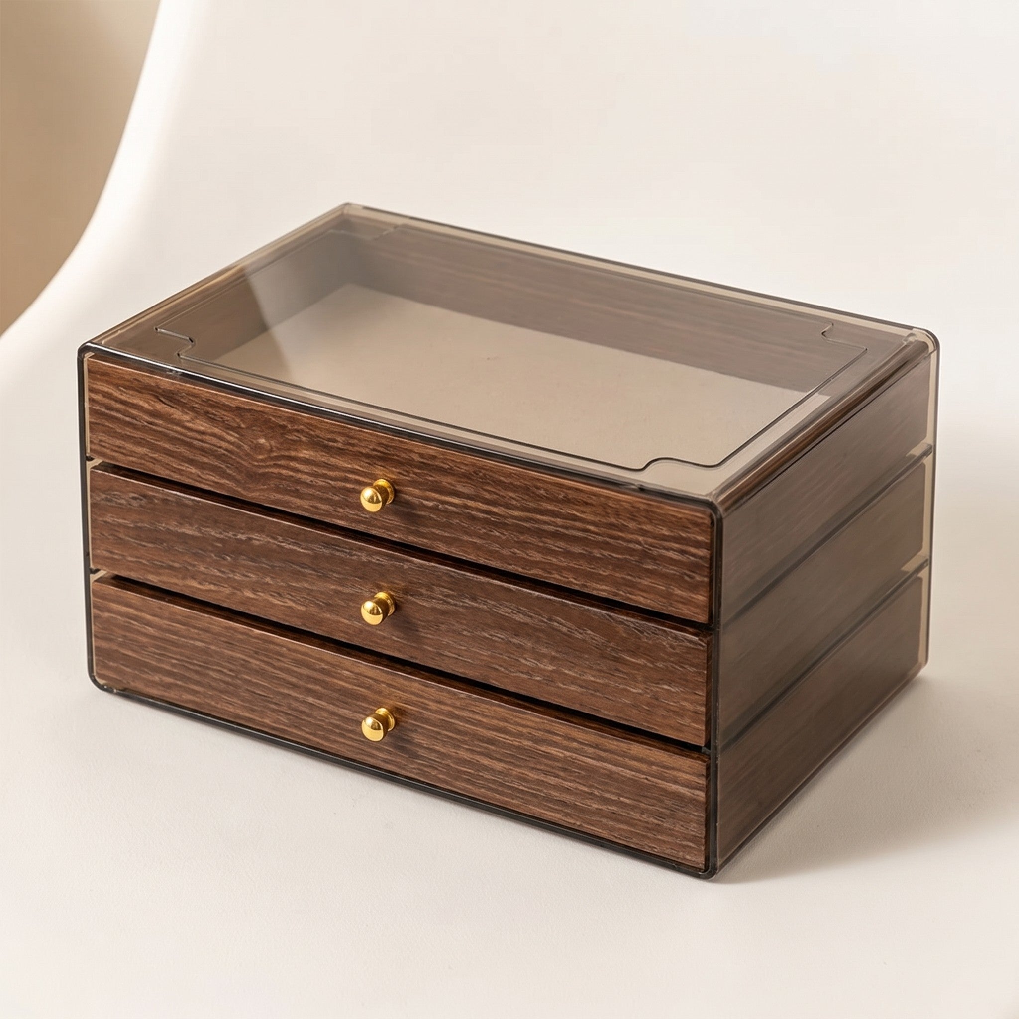 Warm Wood-Grain Tiered Jewelry Box closed on an off-white studio backdrop, showing the clear lid and three drawer fronts.