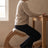 Side view of a person seated on the Ergonomic Rocking Kneeling Chair at a desk, weight forward on the seat pad with shins on the lower pad.