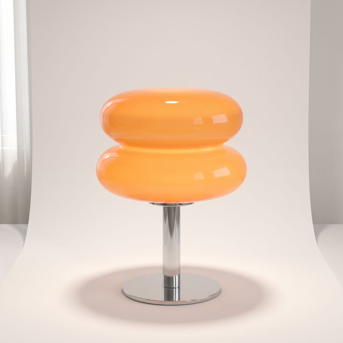 Orange Macaron Glass Table Lamp lit on an off-white studio backdrop, showing its two stacked glass discs and round chrome base.