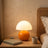 Opal Glass Mushroom Table Lamp on a bedside table beside a cane headboard and oatmeal linen bedding