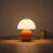 Opal Glass Mushroom Table Lamp dimmed to a low warm glow on a wooden desk at dusk