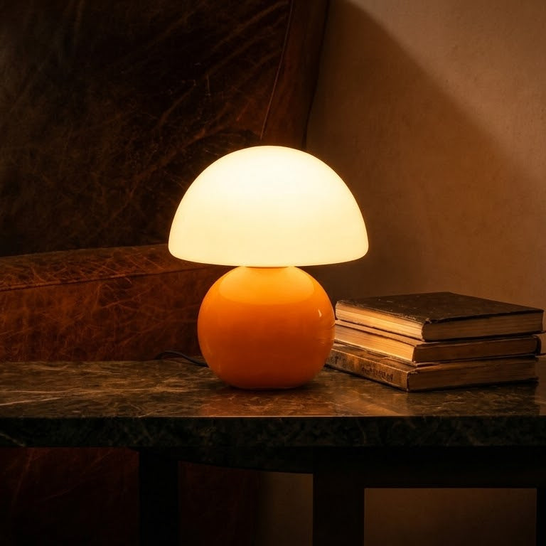 Opal Glass Mushroom Table Lamp lit on a dark side table beside a stack of books