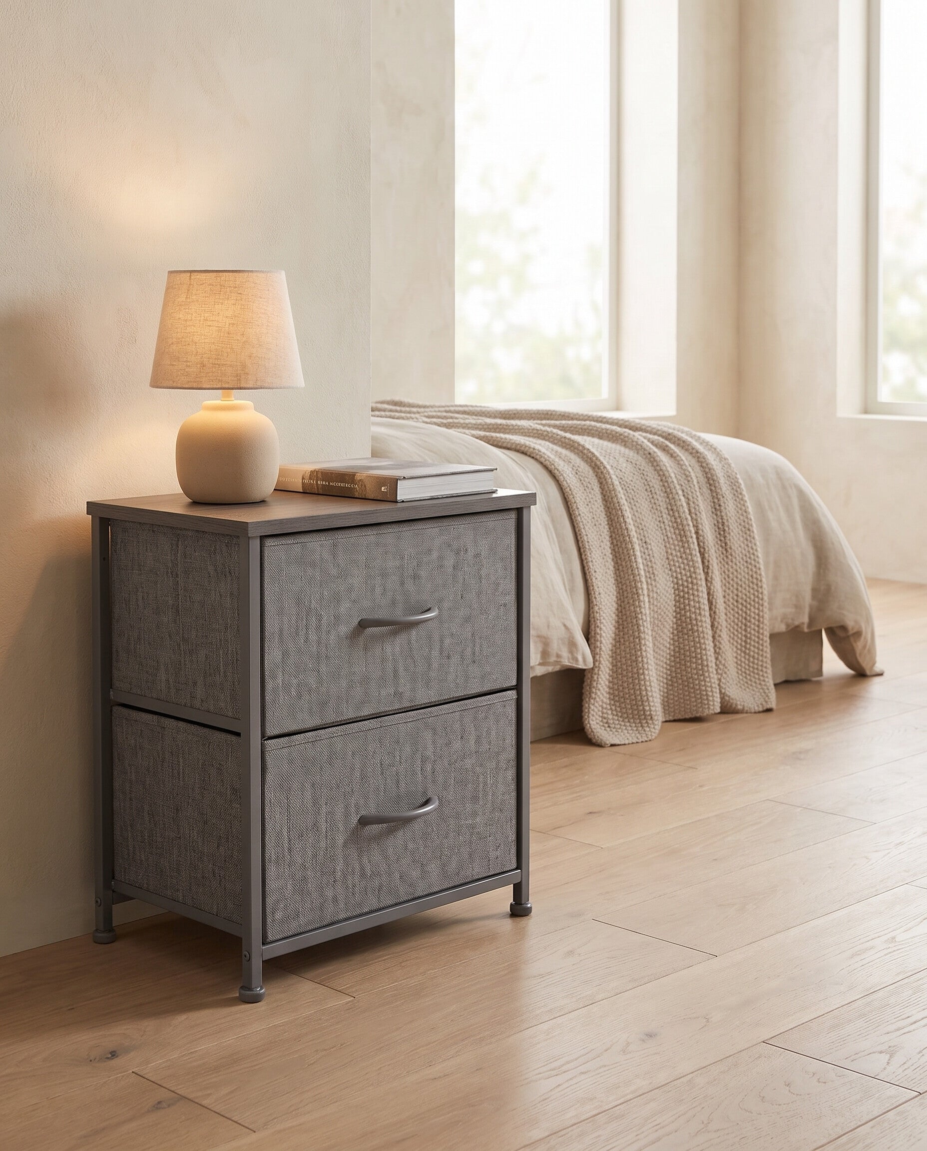 Fabric drawer nightstand in gray in a minimalist bedroom with a lamp and book on top, white oak flooring
