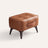 Tufted faux leather ottoman in brown, white studio packshot