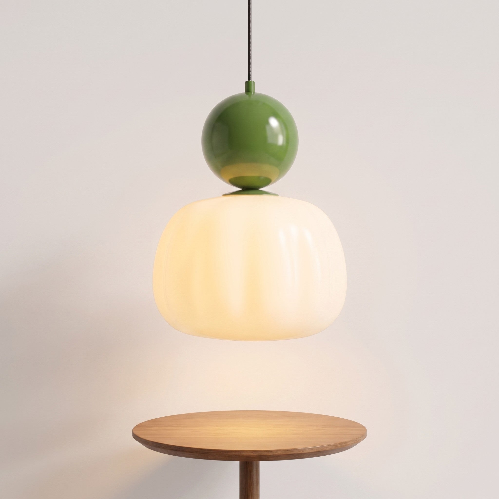 Single-head green pumpkin pendant light lit above a table