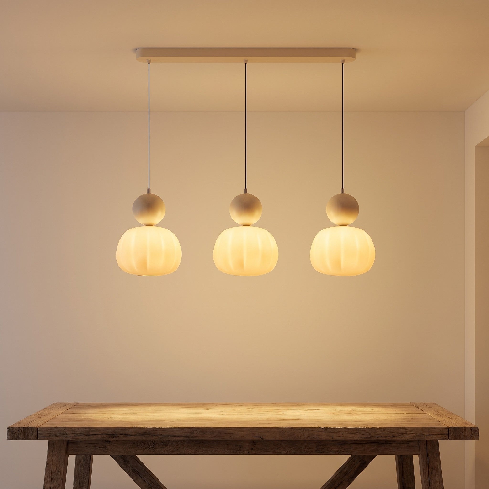 Three-head beige pumpkin pendant light lit above a dining table