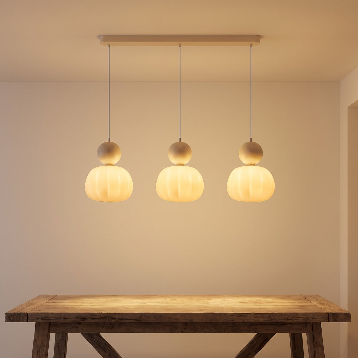 Three-head beige pumpkin pendant light lit above a dining table