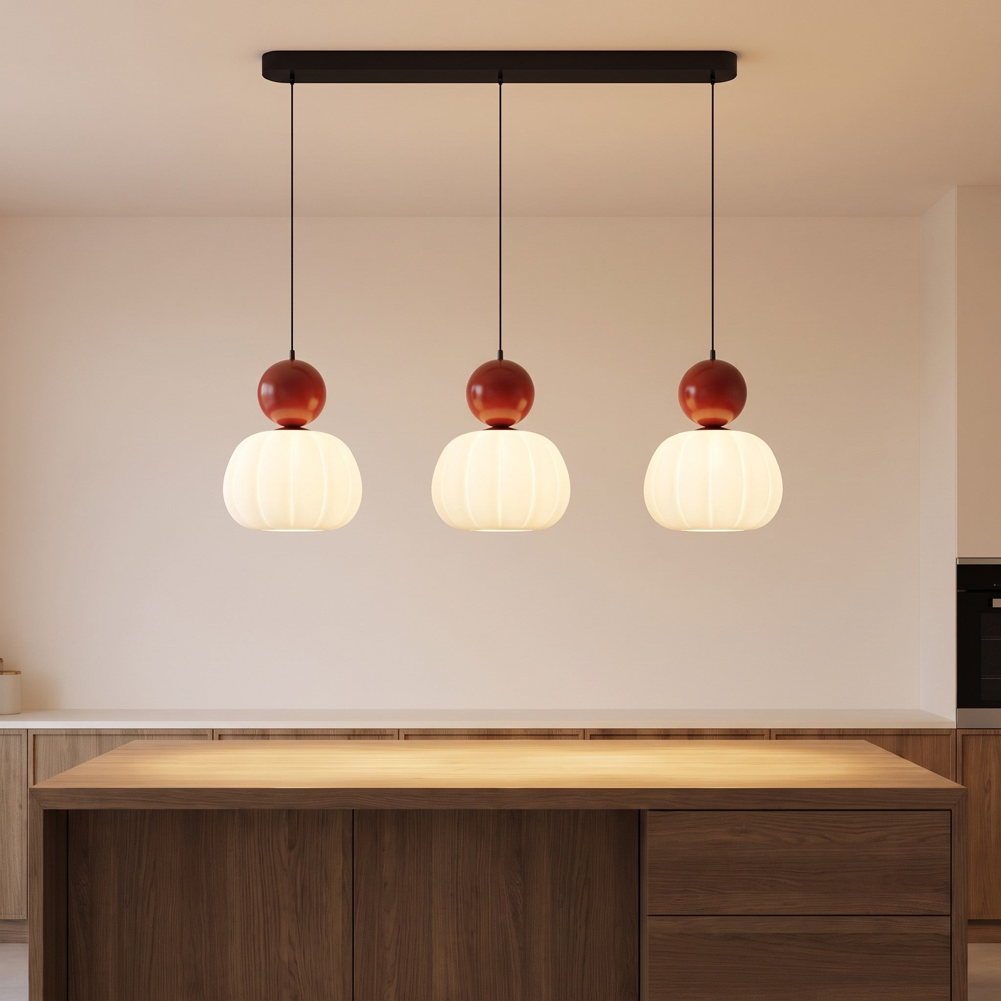 Three-head red pumpkin pendant light lit above a kitchen island