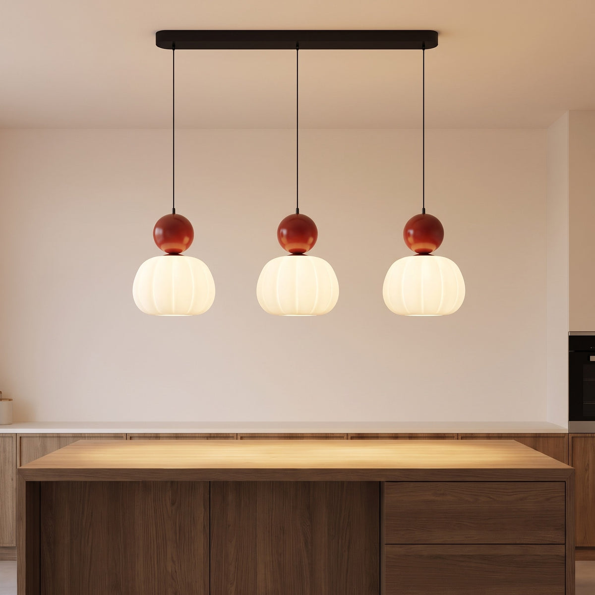 Three-head red pumpkin pendant light lit above a kitchen island