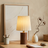 Table lamp on a wooden surface with decorative items and a framed abstract painting in the background.