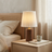 Bedroom scene with a wooden nightstand, lamp, and books.