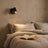 Reading light lit beside a bed with linen bedding and an open book