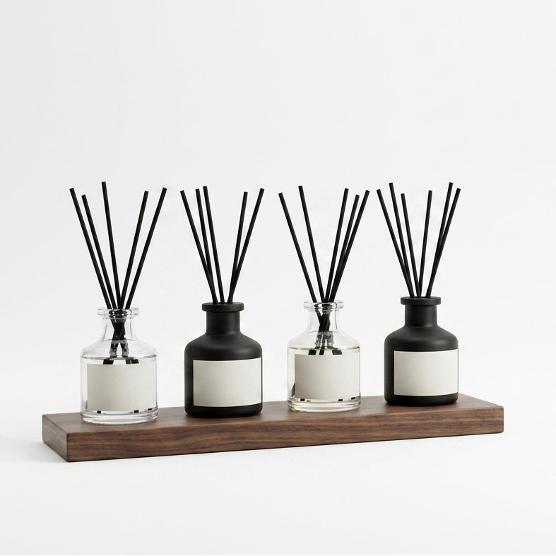 Set of five diffusers with black and clear containers on a wooden shelf against a white background