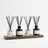 Set of five diffusers with black and clear containers on a wooden shelf against a white background