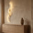 Ribbon curve wall sconce in gold, lit above a white oak sideboard