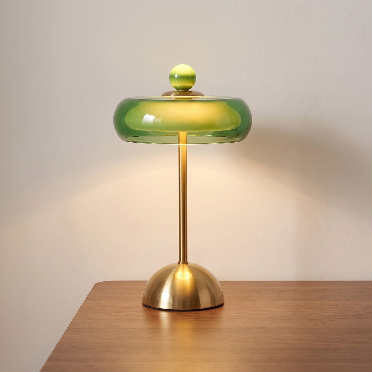 Green glass ring table lamp lit on a desk