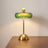 Green glass ring table lamp lit on a desk