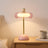 Pink glass ring table lamp lit on a bedside table