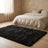 Black shag area rug beside a bed with oatmeal linen bedding