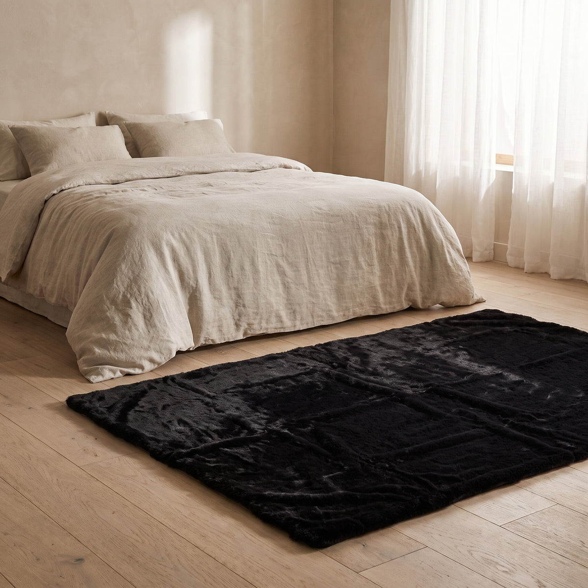 Black plush faux-fur rug beside a bed with oatmeal linen bedding