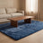 Mottled blue plush faux-fur rug under a walnut coffee table on a pale oak floor