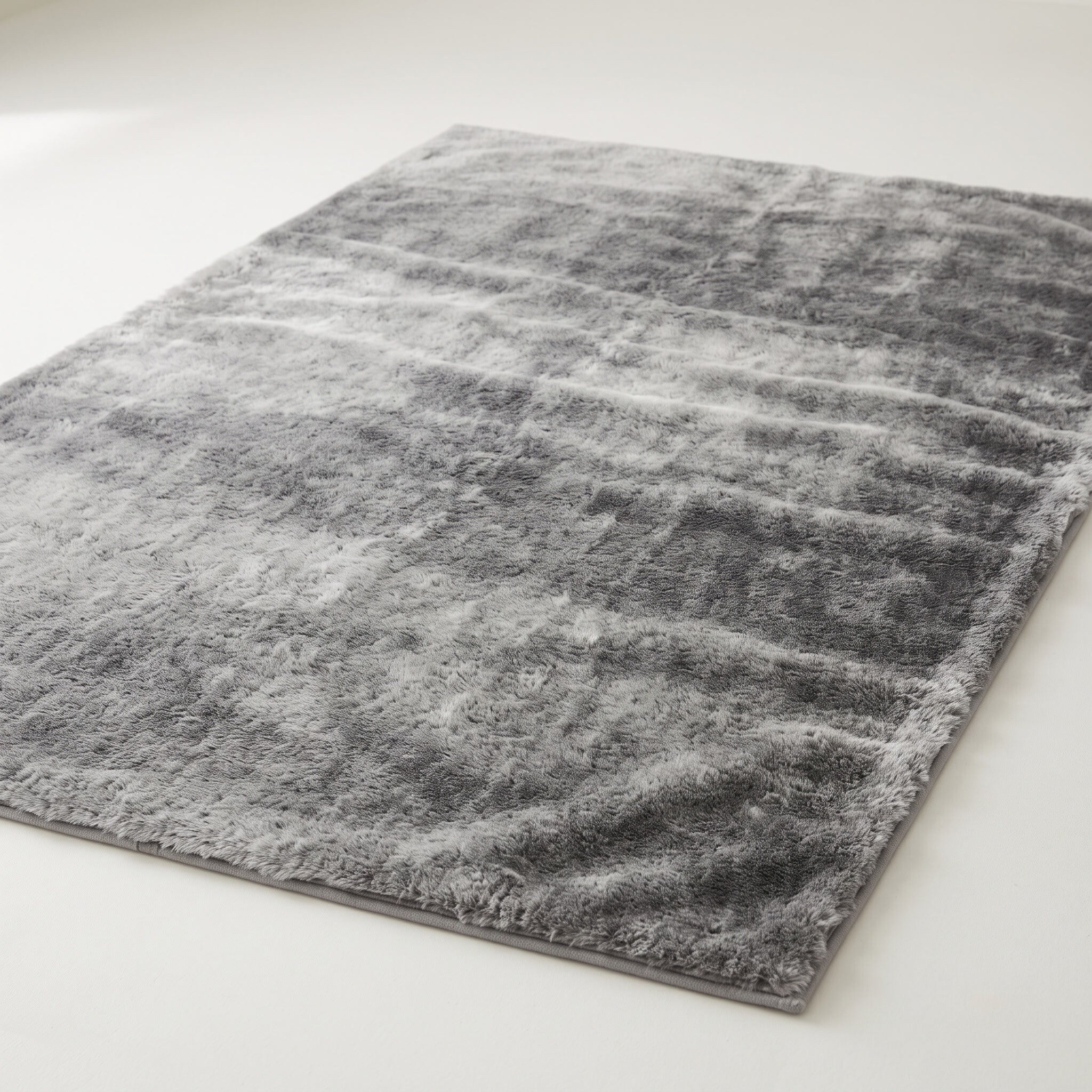 Plush faux-fur area rug in mottled gray on a plain off-white background