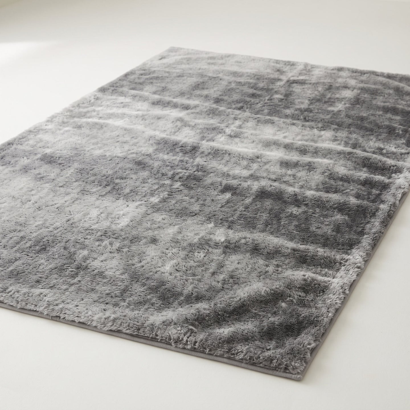 Plush faux-fur area rug in mottled gray on a plain off-white background