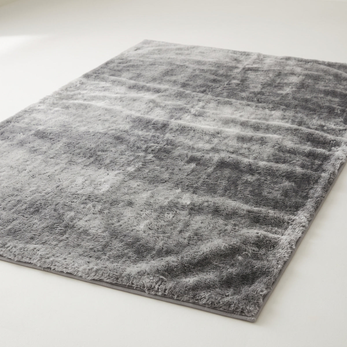 Plush faux-fur area rug in mottled gray on a plain off-white background