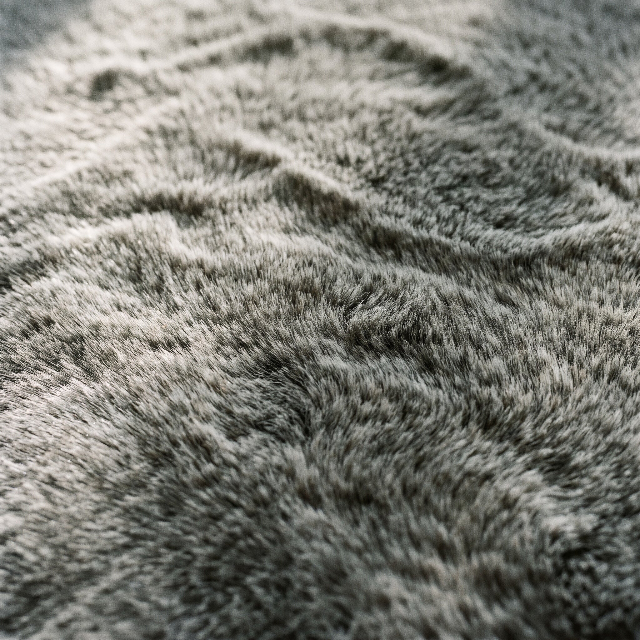 Close-up of the dense velvety faux-fur pile of the area rug in mottled gray