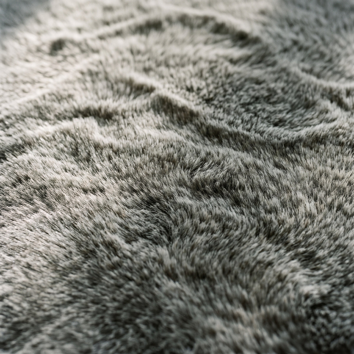 Close-up of the dense velvety faux-fur pile of the area rug in mottled gray