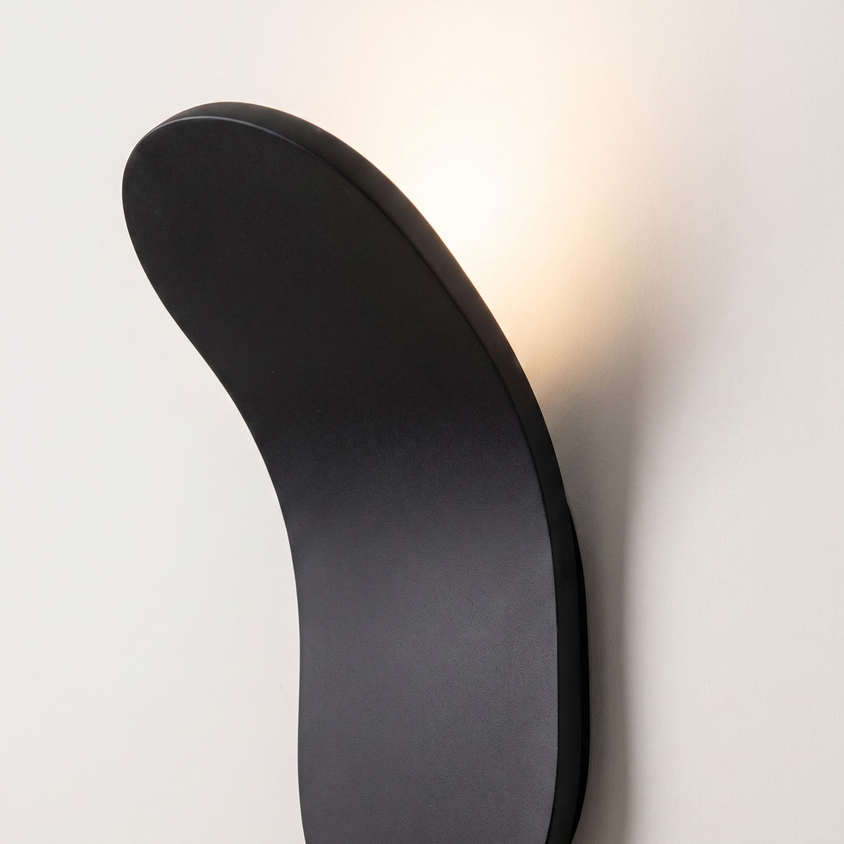 Close-up of curved metal LED wall sconce in black