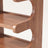 Close-up detail of the curved wood-grain shelf edge and joinery on the corner shoe rack